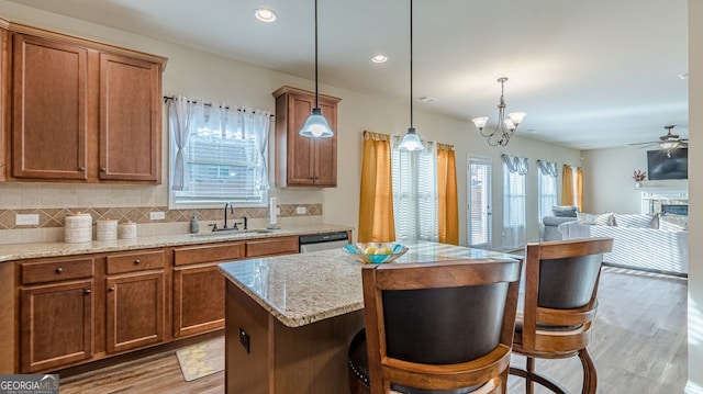 kitchen with decorative backsplash, brown cabinets, a sink, and stainless steel dishwasher