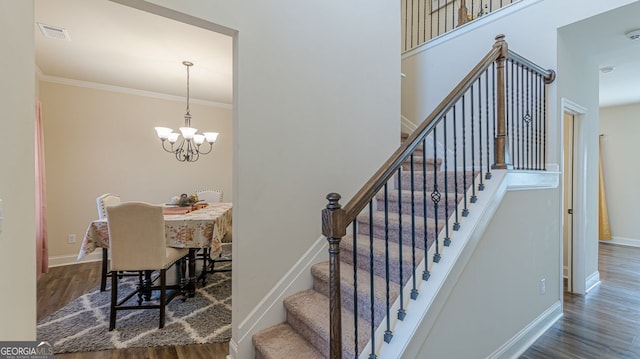 staircase with a chandelier, wood finished floors, visible vents, baseboards, and ornamental molding