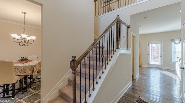 stairway with a chandelier, crown molding, baseboards, and wood finished floors