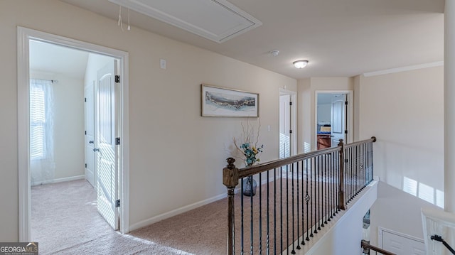 hall with attic access, baseboards, carpet flooring, and an upstairs landing