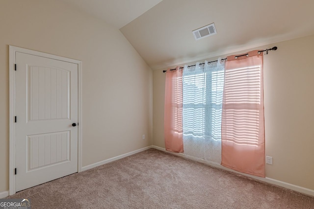 spare room featuring carpet floors, visible vents, vaulted ceiling, and baseboards