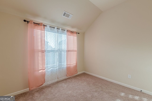 carpeted spare room featuring visible vents, vaulted ceiling, and baseboards