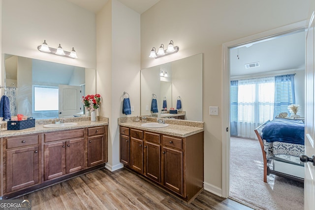 bathroom featuring visible vents, two vanities, a sink, and wood finished floors