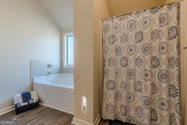 full bath featuring curtained shower, vaulted ceiling, a bath, and wood finished floors