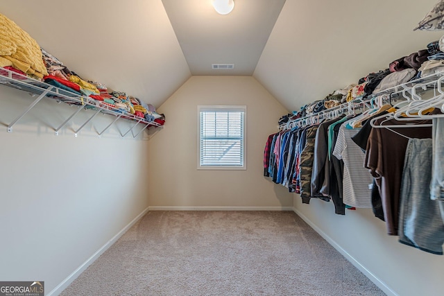 spacious closet with carpet floors, visible vents, and lofted ceiling