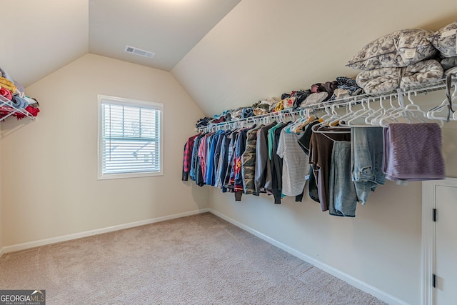 spacious closet with carpet floors, lofted ceiling, and visible vents