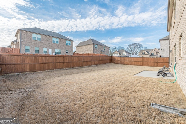 view of yard with a residential view, a fenced backyard, and a patio