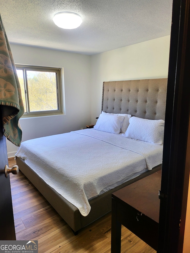 bedroom with a textured ceiling and wood finished floors