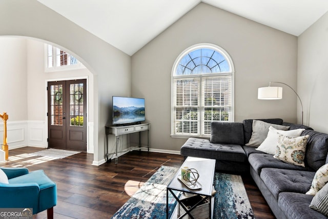 living area with arched walkways, french doors, a wainscoted wall, vaulted ceiling, and wood finished floors