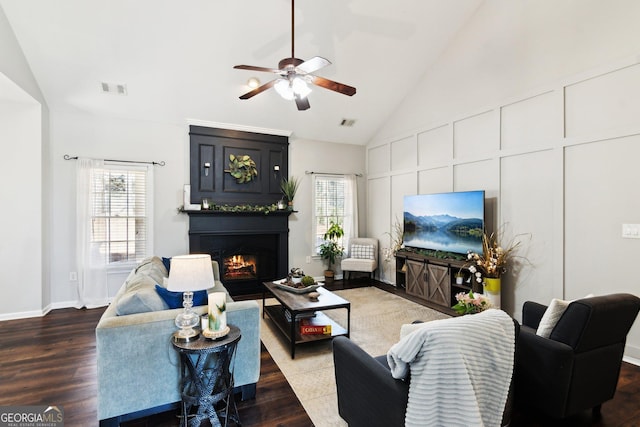 living room featuring a warm lit fireplace, visible vents, a wealth of natural light, and wood finished floors