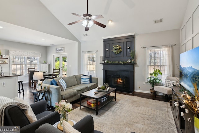 living area with a warm lit fireplace, visible vents, a wealth of natural light, and baseboards