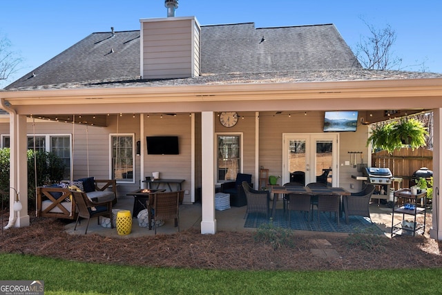 back of property with a shingled roof, a patio area, and fence