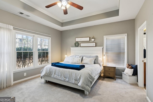 bedroom featuring visible vents, baseboards, light colored carpet, a tray ceiling, and crown molding