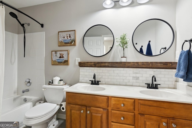 full bathroom with toilet, double vanity, backsplash, and a sink