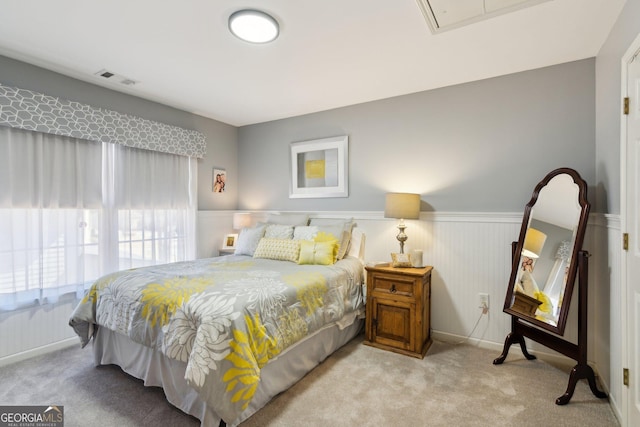 bedroom featuring carpet, visible vents, attic access, and wainscoting