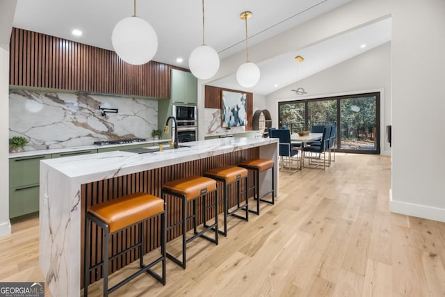 kitchen with light wood finished floors, modern cabinets, appliances with stainless steel finishes, vaulted ceiling, and backsplash