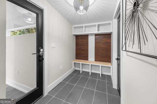 mudroom with dark tile patterned flooring and baseboards