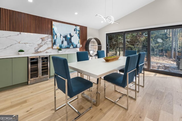 dining room with lofted ceiling, beverage cooler, light wood finished floors, and recessed lighting