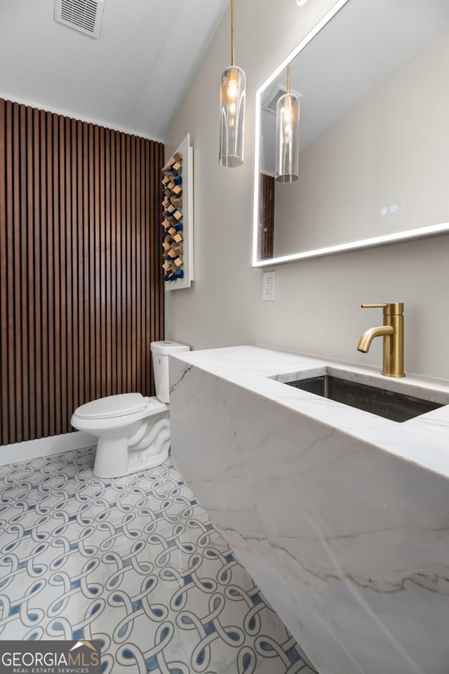 bathroom with visible vents, toilet, vaulted ceiling, a sink, and tile patterned floors