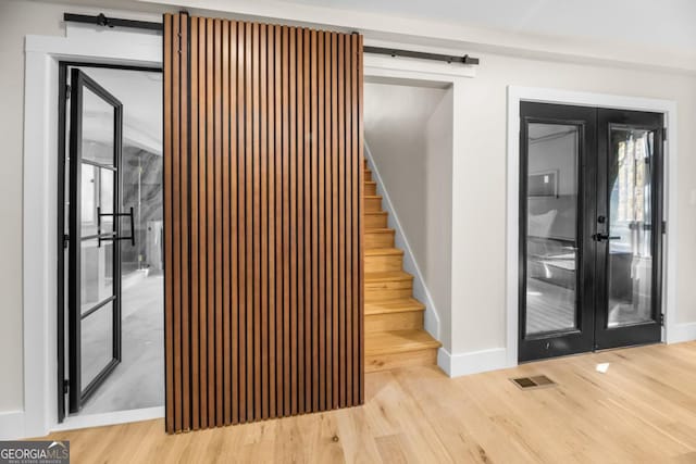 stairs featuring a barn door, visible vents, wood finished floors, and french doors