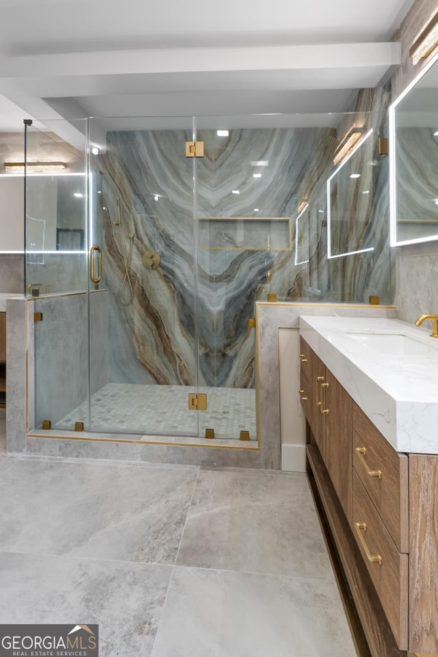 full bath featuring a marble finish shower, vanity, and tile walls