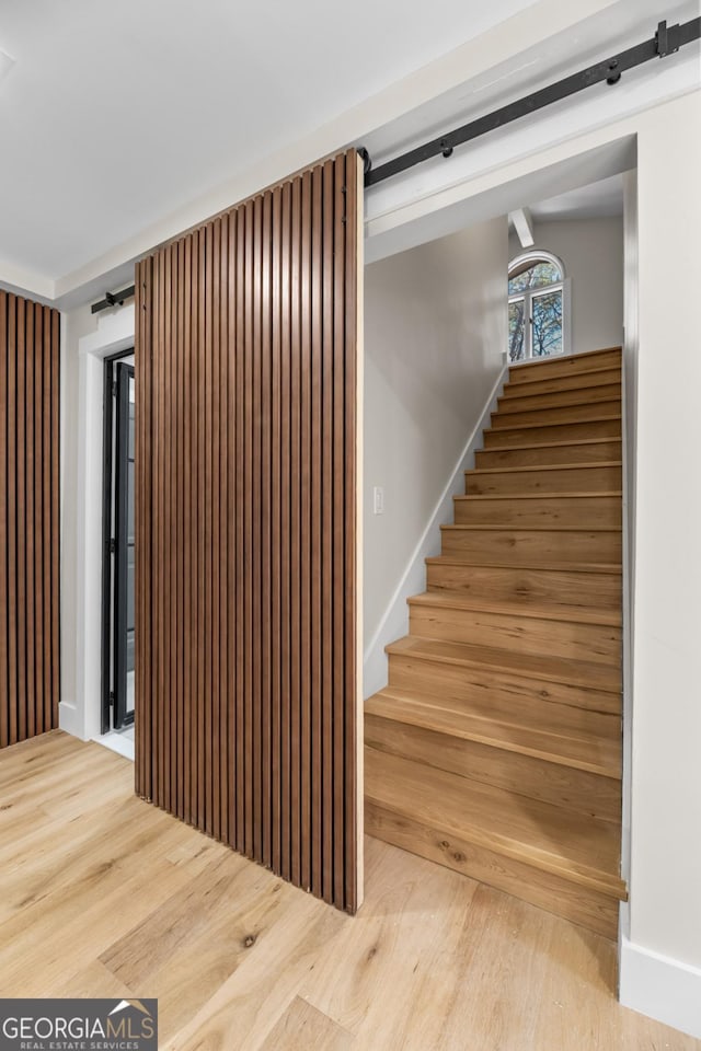 staircase with wood finished floors, baseboards, and a barn door