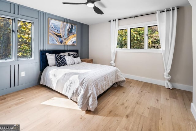 bedroom with light wood-style floors, ceiling fan, and baseboards