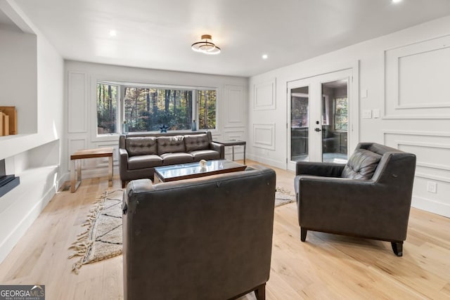 living room featuring french doors, light wood-type flooring, and a decorative wall