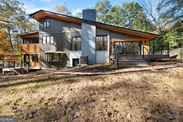 exterior space featuring a chimney, central AC unit, and a wooden deck