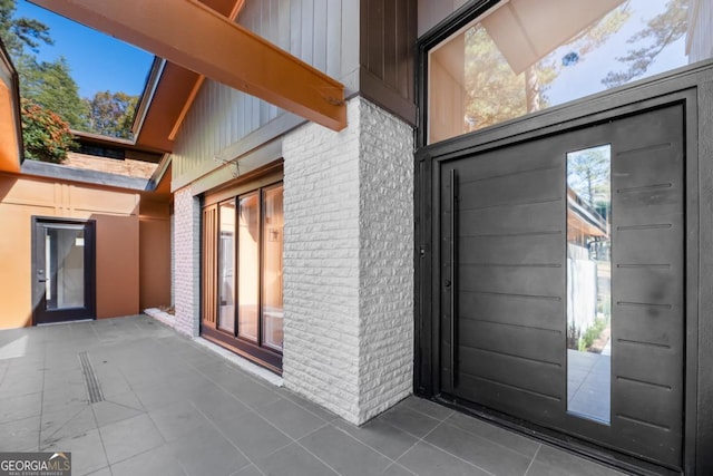 entrance to property featuring a patio and brick siding