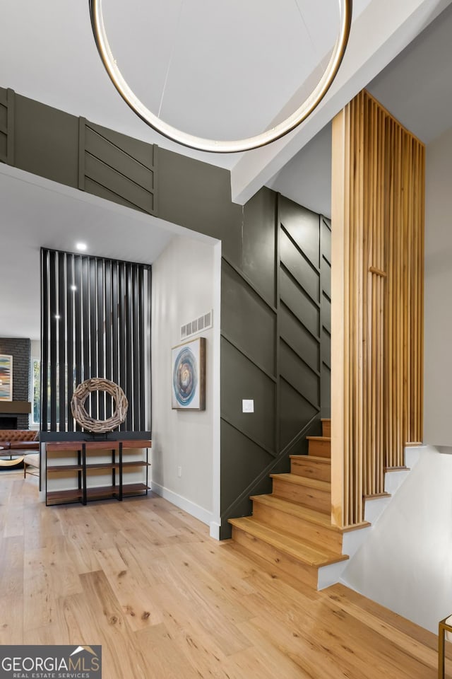 staircase featuring wood finished floors, visible vents, and baseboards