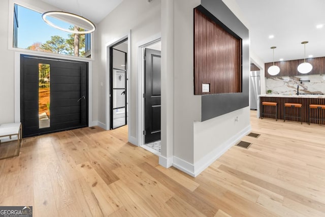 entryway featuring light wood-style flooring, visible vents, and baseboards