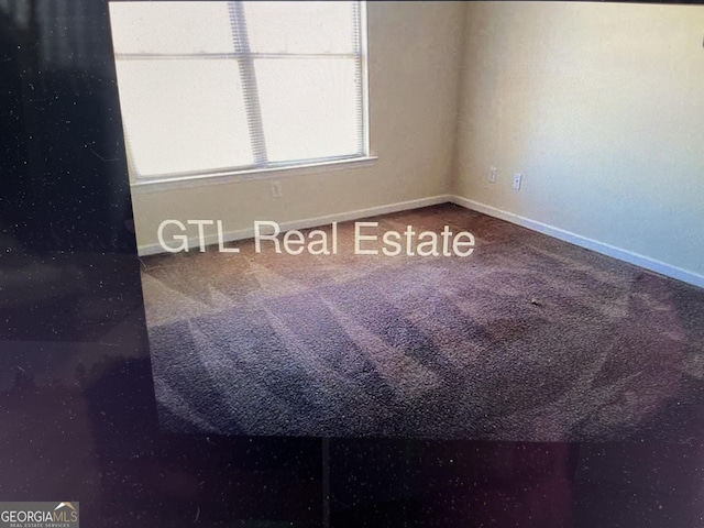 carpeted empty room featuring baseboards