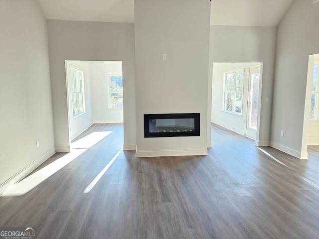 unfurnished living room featuring a healthy amount of sunlight, wood finished floors, and a glass covered fireplace