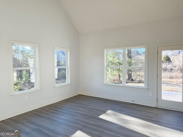 spare room featuring baseboards, vaulted ceiling, and dark wood-style flooring