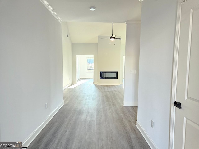 corridor with ornamental molding, wood finished floors, and baseboards