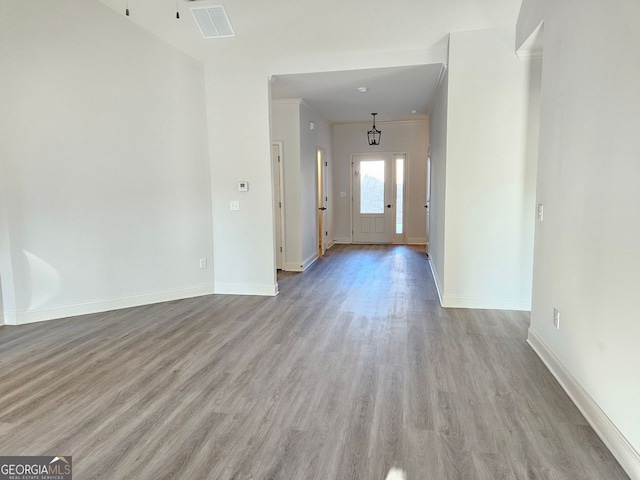 foyer entrance featuring light wood finished floors, baseboards, visible vents, and ornamental molding