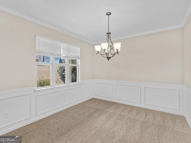 empty room with carpet floors, a wainscoted wall, a chandelier, and crown molding