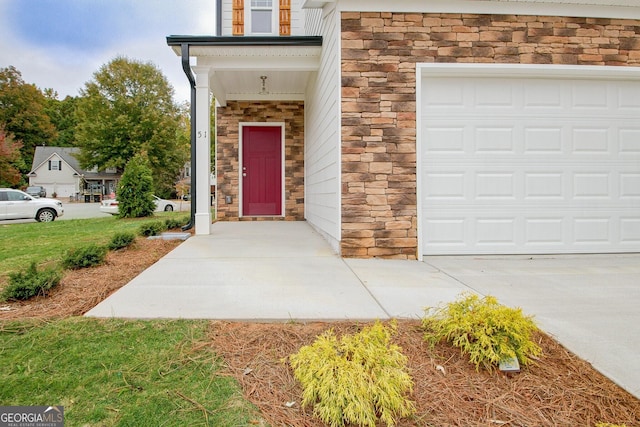 entrance to property with a garage and stone siding