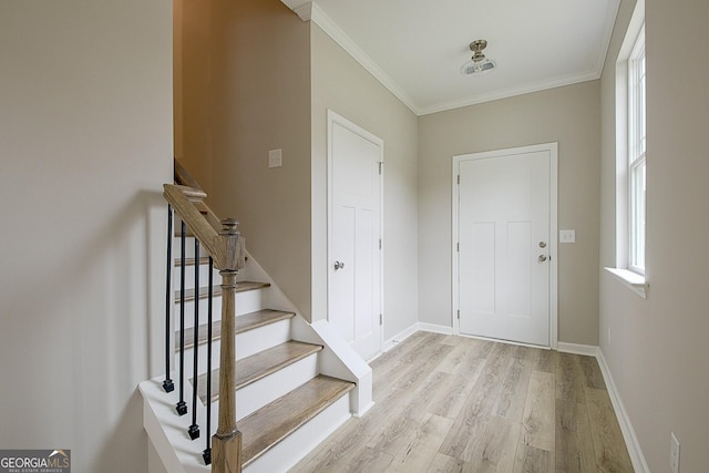 entryway with light wood-style floors, stairway, baseboards, and crown molding