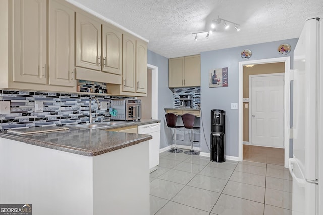 kitchen with backsplash, light tile patterned flooring, a textured ceiling, white appliances, and a peninsula