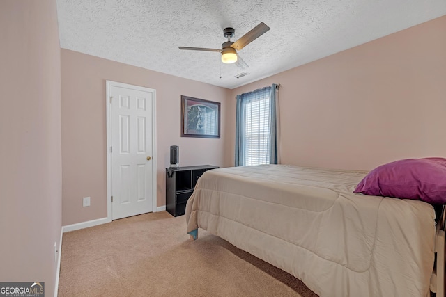 bedroom with light carpet, baseboards, visible vents, ceiling fan, and a textured ceiling