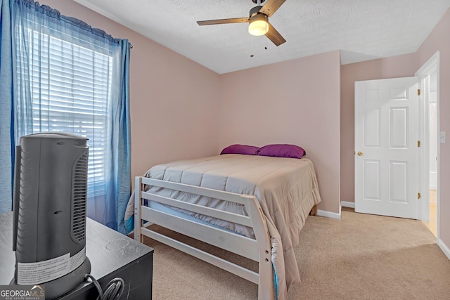 bedroom with light carpet, ceiling fan, a textured ceiling, and baseboards