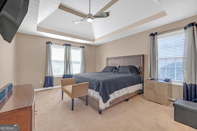 bedroom with a tray ceiling, light carpet, and a textured ceiling