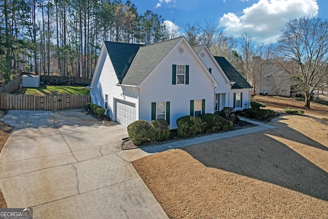 view of front facade featuring a garage, concrete driveway, a shingled roof, and fence