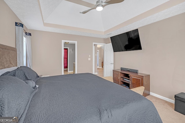 bedroom with a textured ceiling, light carpet, a ceiling fan, baseboards, and a raised ceiling