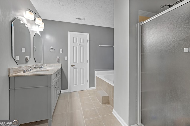 full bath featuring a textured ceiling, tile patterned flooring, a garden tub, double vanity, and a stall shower