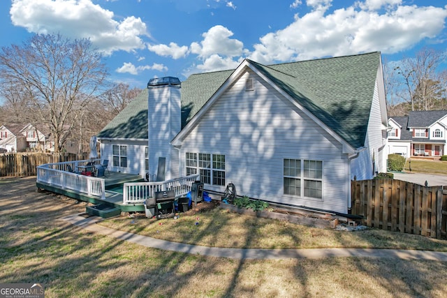 back of property featuring fence, a deck, and a lawn