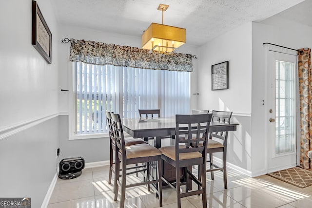 dining area with light tile patterned floors, baseboards, and a textured ceiling