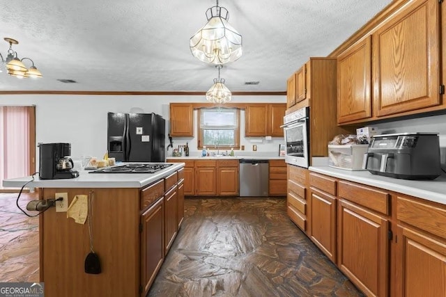 kitchen with stainless steel appliances, ornamental molding, brown cabinetry, and a sink